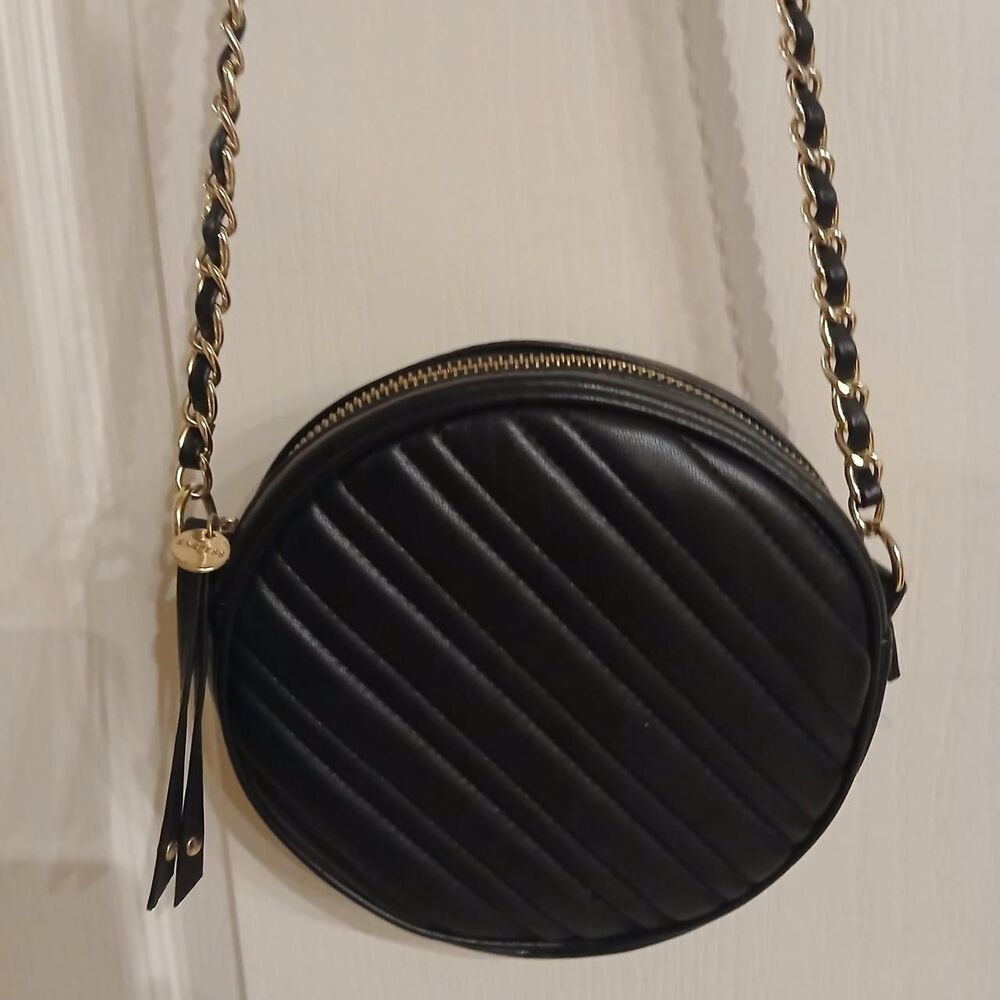 Black round faux leather quilted crossbody bag with gold chain strap and tassel